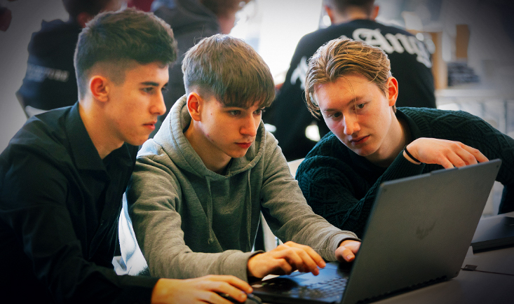 Trije udeleženci med sedijo za računalnikom med hekatlonom, ki ga je organiziral Telemach v okviru JobLab-a